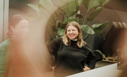 Uśmiechnięta kobieta przed roślinami.